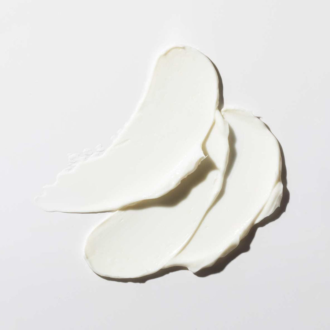 Three swatches of white cream on a light gray background
