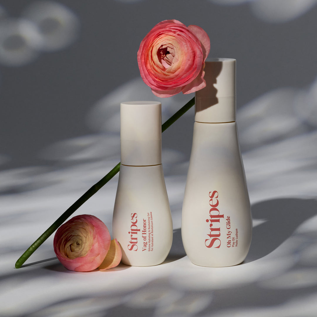Vag of Honor and Oh My Gide Stripes Beauty bottles with pink flowers on a textured surface